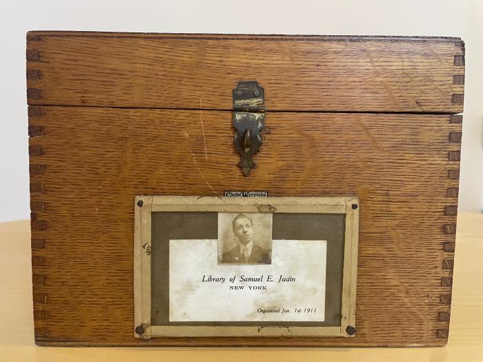 The front of a wooden card catalogue, labeled "Library of Samuel E. Judin, New York, Organized Jan. 1st 1911" with a picture of Samuel Judin