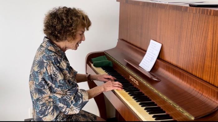Woman in blue printed blouse plays the piano