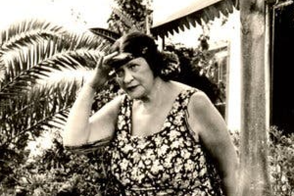 The author Miriam Karpilove with a floral dress and a leaf in her hair.
