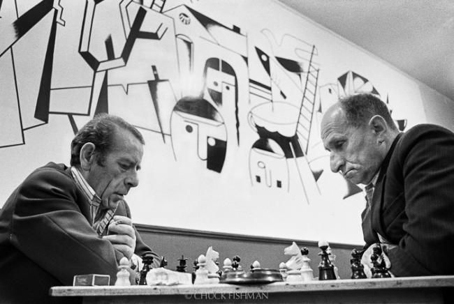 Black and white photograph of two men playing chess in a cafe.