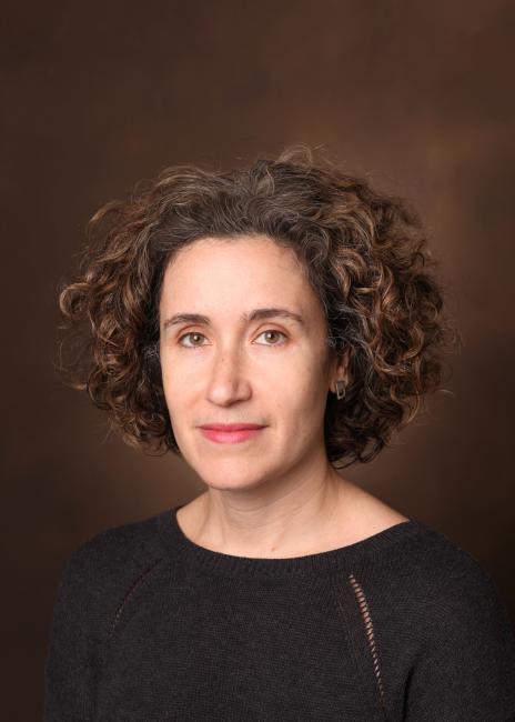 Portrait of Allison Schachter, wearing a black shirt with, with short curly brown hair.