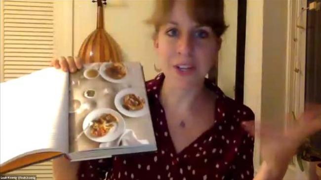 Leah Koenig holds up a cookbook open to images of food
