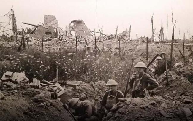 Three soldiers stand in a trench, debris surrounds them, sepia toned