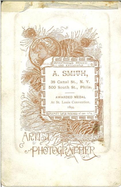 Backside of a portrait photograph, featuring a feathery graphic. Text reads: A. Smith, 38 Canal St, N.Y., 500 South St., Phila. Awarded medal at St. Louis convention, 1894.