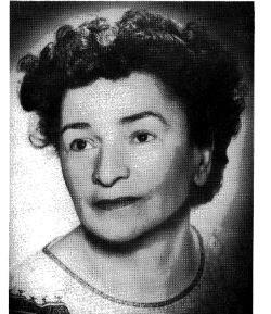Black and white photo of a woman in a white and black blouse with curly hair.