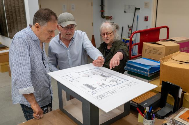 Three people gather around a floorplan