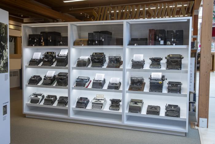 Wall of typewriters behind glass case