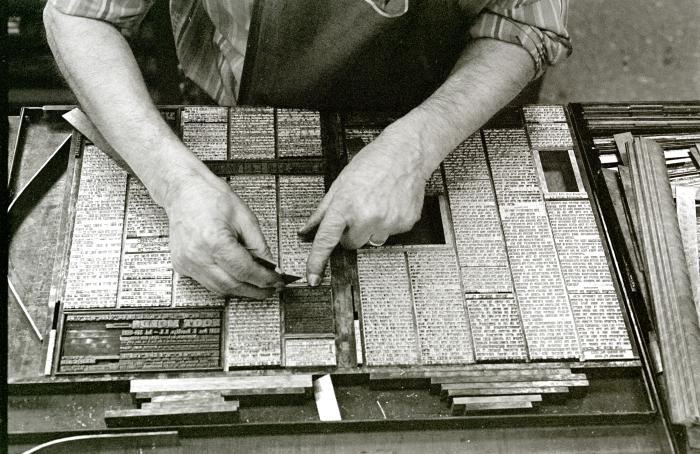 Hands work on typeset, black and white photograph