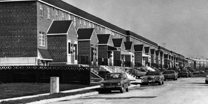 Row homes with cars parked in front, black and white photo