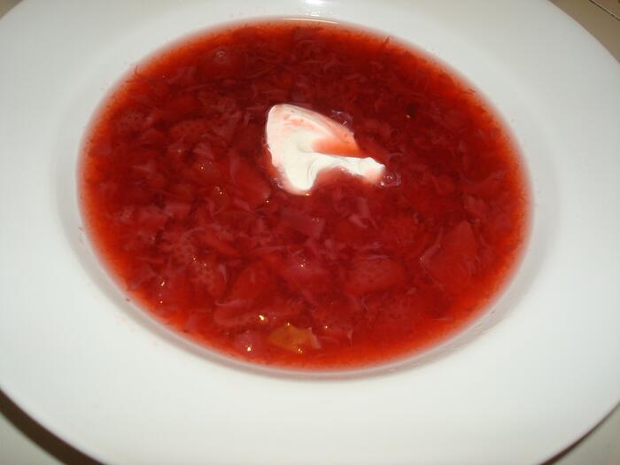 Strawberry borscht in a bowl with sour cream