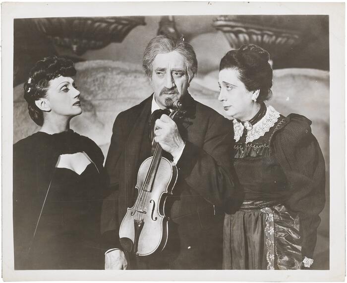 A photo of the Yiddish actors Luba Kadison, Maurice Schwartz, and Berta Gersten in the play "The Three Gifts," 1945, Schwartz holding a violin.