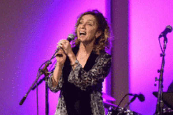 Eleanor singing with a purple background. 