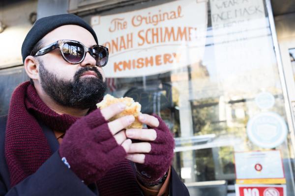 Michael wearing sunglasses and eating a knish. 