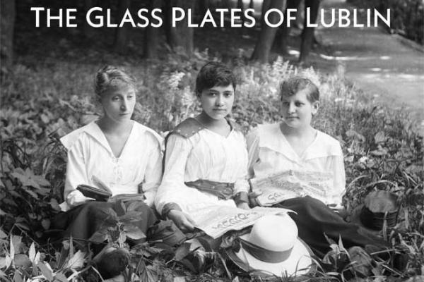 book cover for "The Glass Plates of Lublin," a black and white photo of three women reading Yiddish periodicals in a park field
