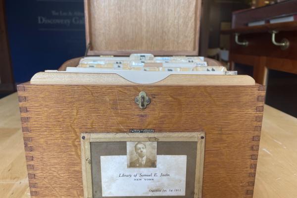 Open wooden card catalogue with white Yiddish index cards, labeled Library of Samuel E. Judin New York Organized Jan. 1st 1911