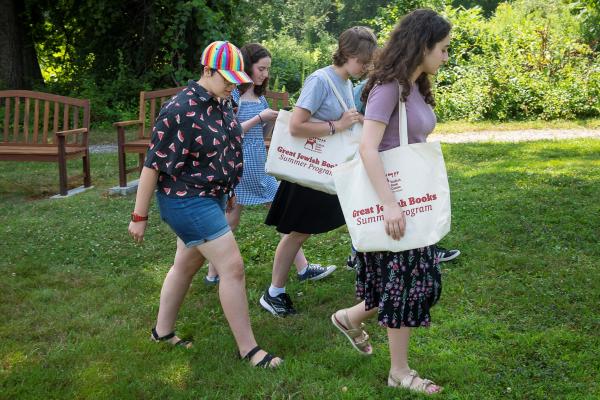 a group of four students walking and smiling with bags