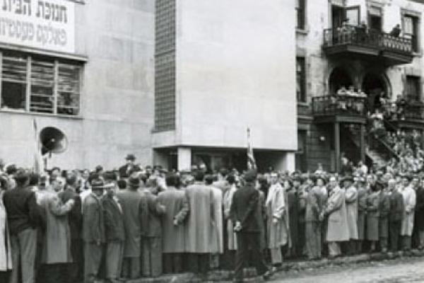 Black and white image of a line of people outside a library building in the 1950s. 