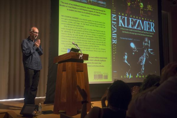 A man lectures in front of a powerpoint slide on klezmer